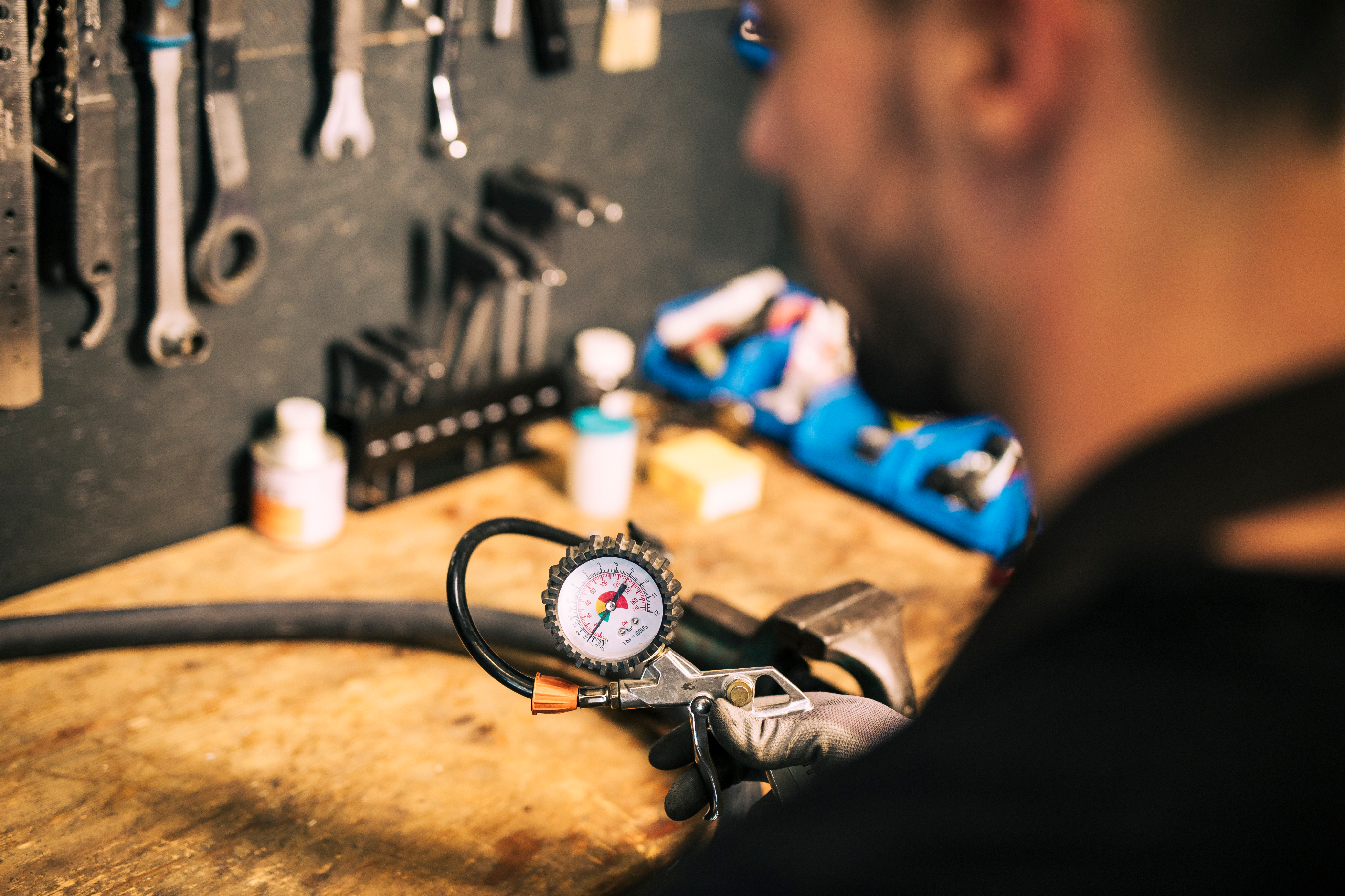 Technician using a pressure gauge at the cylinder retesting workbench